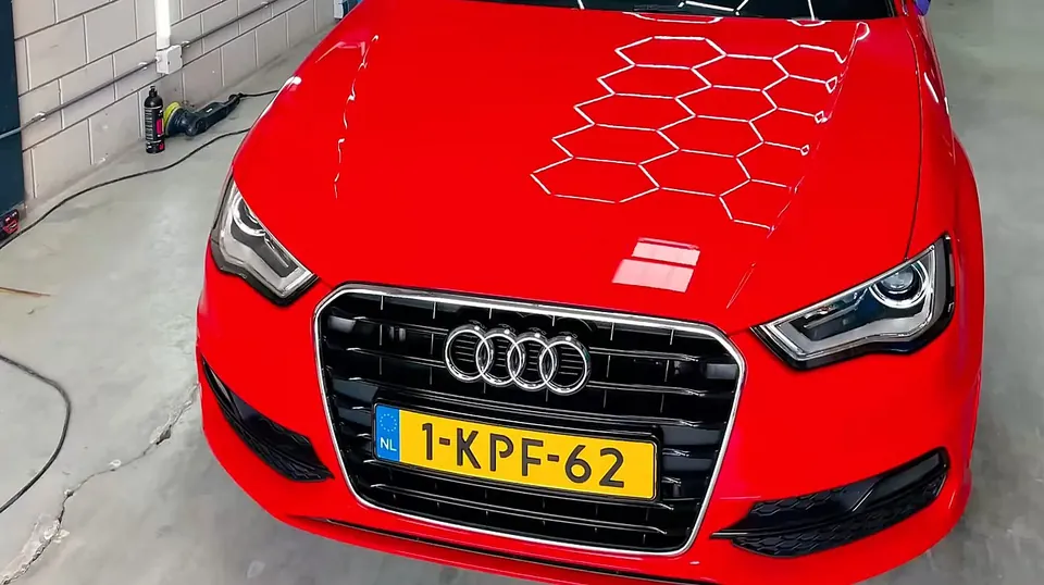 Rode Audi A3 met de hexagonale lampen gespiegeld in de gepolijste motorkap