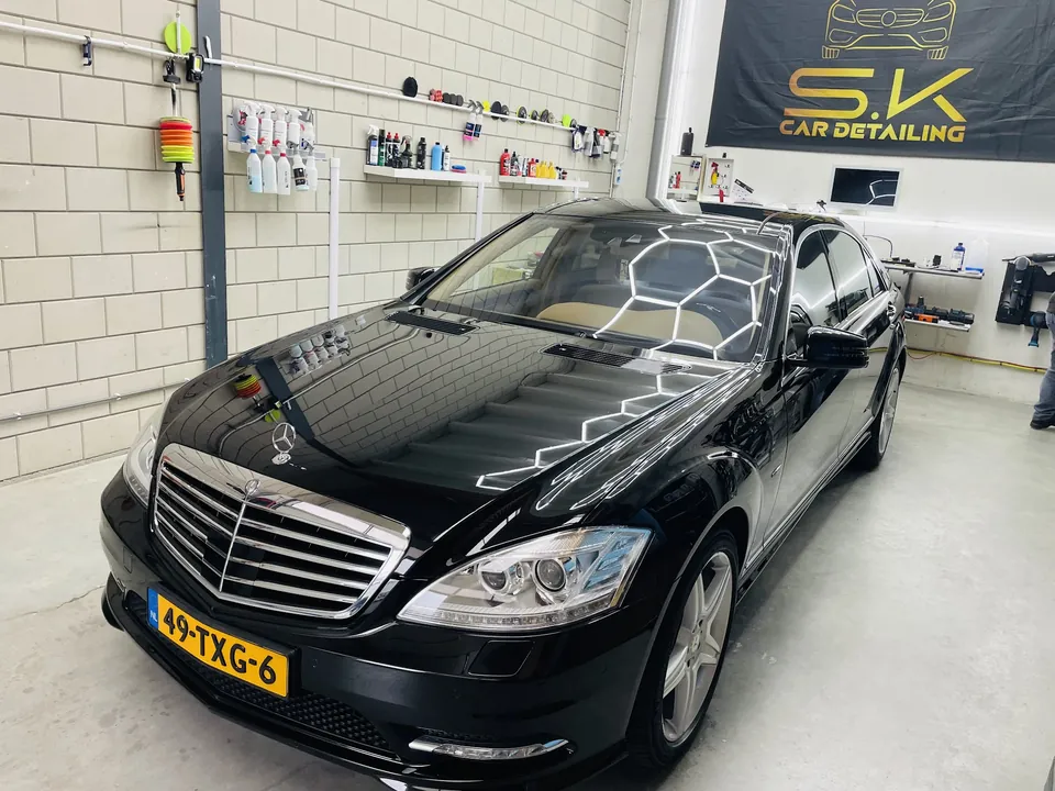 Zwarte Mercedes-Benz S400 Hybrid in onze studio, met ons logo aan de muur